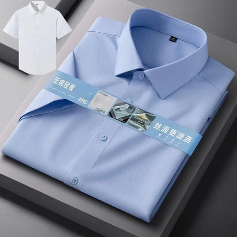 A folded light blue long-sleeve dress shirt with a pointed collar and button front, shown on a gray display surface.