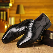 Pair of black dress shoes on a wooden surface with a blurred background