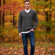 Gray knitted sweater on a hanger against a light gray background