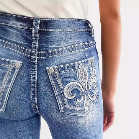 Close-up of blue jeans with a decorative pocket design on a white background