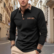 Man wearing a black long-sleeve polo shirt with plaid accents on a city street.