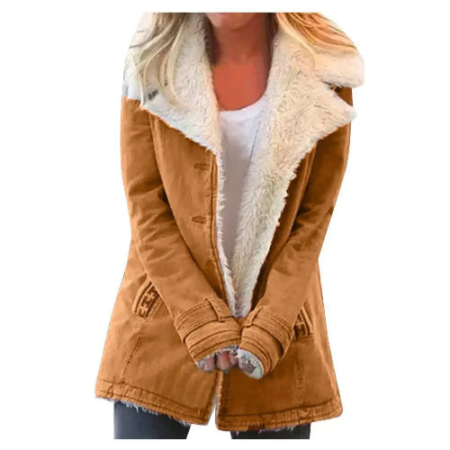 Woman wearing a tan coat with wide cream fleece-look lapels, front pockets and cuff tabs over a white top and dark trousers