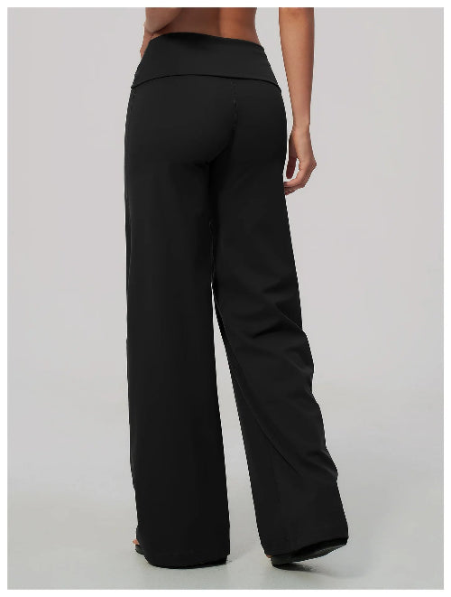 Black wide-leg pants shown from the back on a model, featuring a high-waisted elastic waistband and a relaxed straight-leg silhouette, photographed against a neutral light gray studio background.