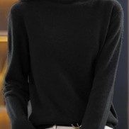 A woman wearing a black long-sleeve turtleneck sweater, paired with off-white pants, shown from the neck down in a close-up shot.