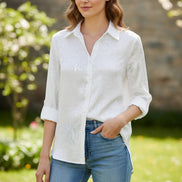 Person wearing a white button-up shirt and blue jeans against a gray background