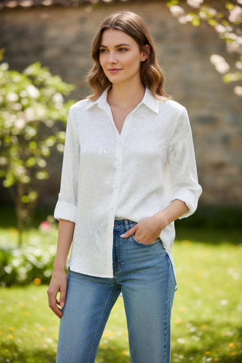Person wearing a white button-up shirt and blue jeans against a gray background