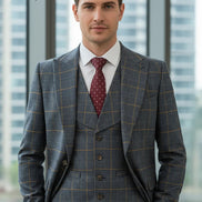 Man wearing a gray checkered suit with a red patterned tie in front of a blurred cityscape.