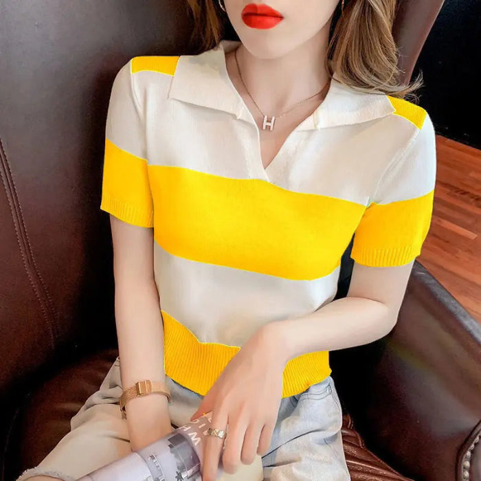 A woman wearing a short-sleeve knit polo shirt with bold horizontal stripes in white and bright yellow, seated on a dark brown leather chair.