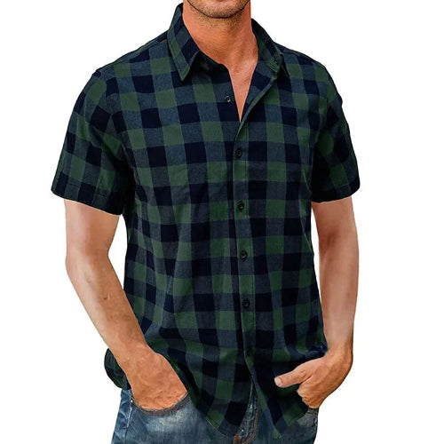 A man wearing a short-sleeve button-up plaid shirt in dark green and black, paired with blue jeans, shown against a plain white background.