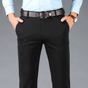 Person wearing black pants with a brown belt on a gray background