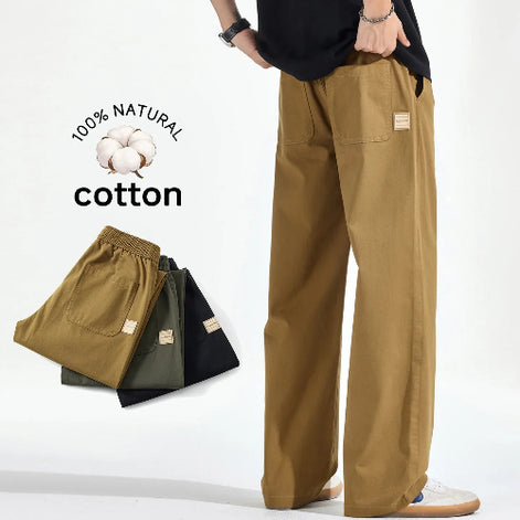 Model wearing khaki loose-fit pants with front patch pockets, alongside folded khaki, army green, and black pairs and a graphic reading 100% natural cotton.