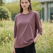 Person wearing a mauve long-sleeve shirt sitting on a chair indoors.