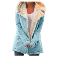 Woman wearing a light blue coat with wide cream fleece-look lapels, front pockets and cuff tabs over a white top and dark trousers