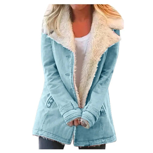 Woman wearing a light blue coat with wide cream fleece-look lapels, front pockets and cuff tabs over a white top and dark trousers