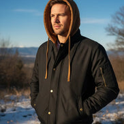 Man wearing a black jacket with a brown hood in a snowy landscape