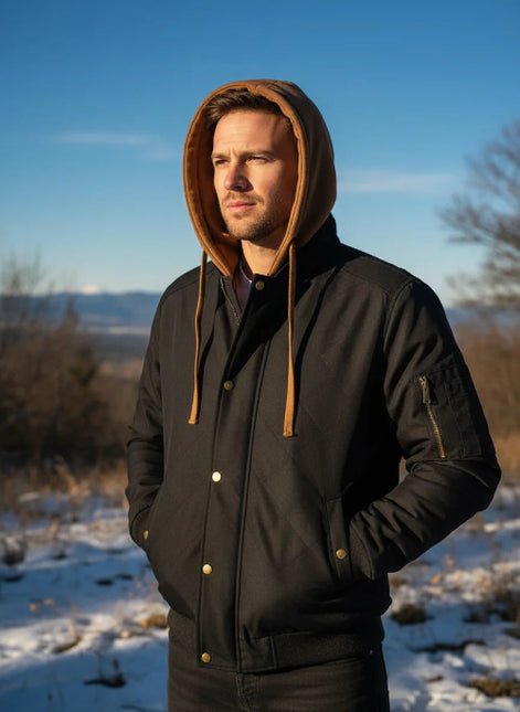 Man wearing a black jacket with a brown hood in a snowy landscape