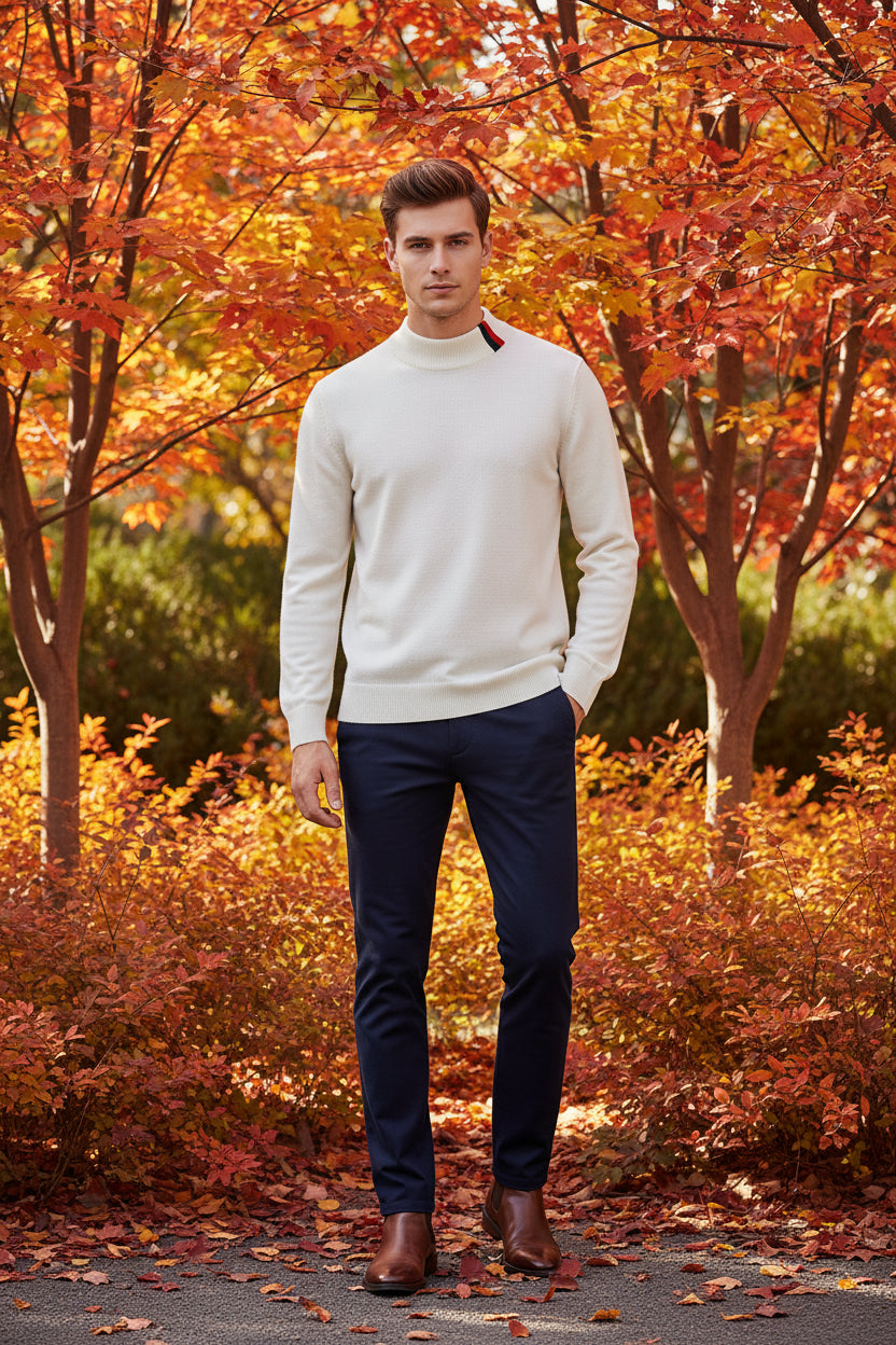 Folded white sweater with a colorful stripe on a black surface, next to a watch.