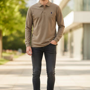 Brown long-sleeve polo shirt with a logo on a hanger in a clothing store.