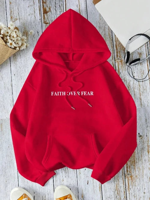Red hoodie with 'Faith Over Fear' text on a wooden surface