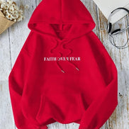 Red hoodie with 'Faith Over Fear' text on a wooden surface