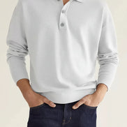 Person wearing a light gray long-sleeve polo shirt against a beige background