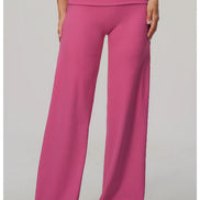 A model wearing bright pink wide-leg pants with a high-waisted, double-erased waistband, shown from the waist down on a light gray studio background.