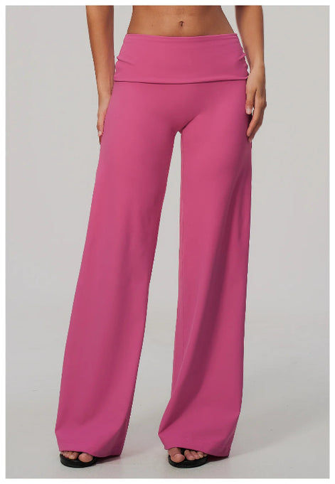 A model wearing bright pink wide-leg pants with a high-waisted, double-erased waistband, shown from the waist down on a light gray studio background.