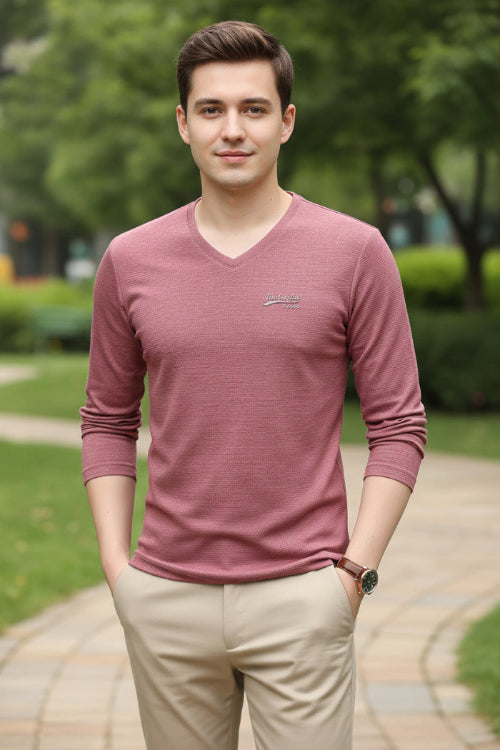 Person wearing a maroon long-sleeve shirt with a logo on a gray background