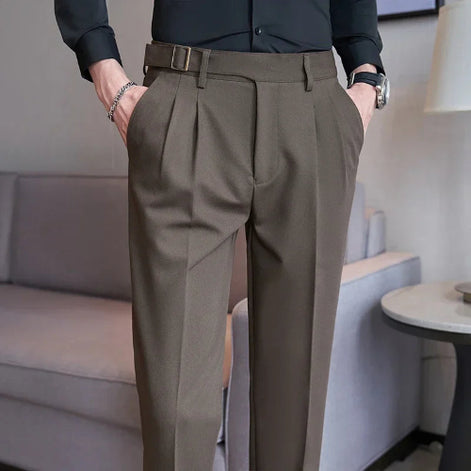 Person wearing brown pleated pants in an indoor setting