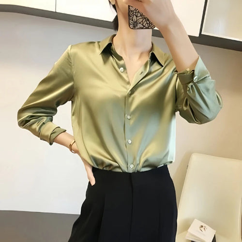 Sage green satin blouse worn by a model taking a mirror selfie.