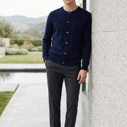 A dark navy blue knit cardigan sweater hanging on a wooden hanger against a plain gray background.