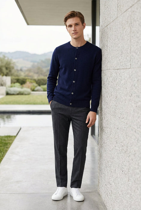 A dark navy blue knit cardigan sweater hanging on a wooden hanger against a plain gray background.