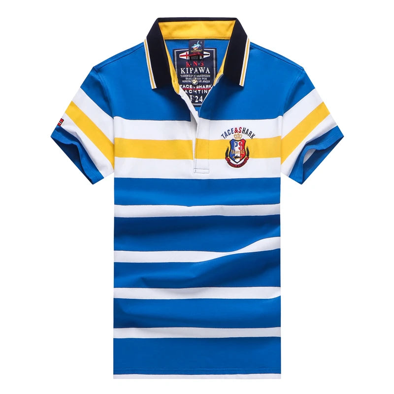 A short-sleeve polo shirt with horizontal blue, white, and yellow stripes, featuring a navy and yellow collar, a 'KIPAWA' brand label inside the neck, and a 'TUESDAY' crest on the left chest.