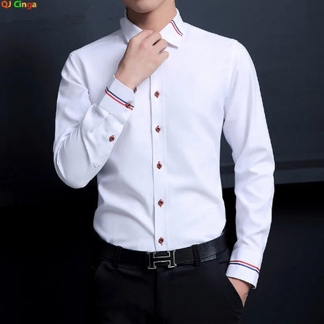 A man wearing a white long-sleeve dress shirt with red and blue striped trim on the cuffs and collar, paired with black trousers and a black belt. The brand logo 'QJ Cinga' 