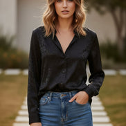 Person wearing a black leopard print shirt against a plain background