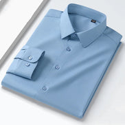 A folded light blue long-sleeve dress shirt with a pointed collar and button front, shown on a clean white background.