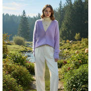 A person wearing a soft fuzzy lavender cardigan over a cream turtleneck 