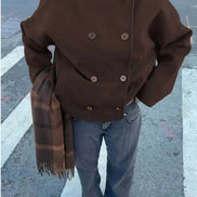 Overhead view of a brown double-breasted short coat styled with jeans and a plaid scarf