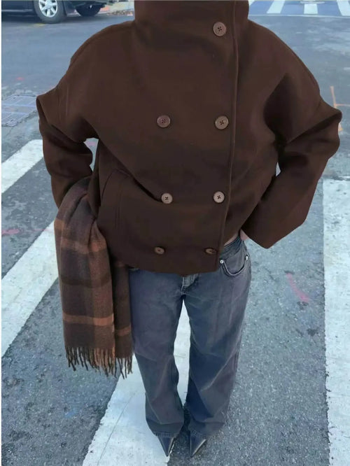Overhead view of a brown double-breasted short coat styled with jeans and a plaid scarf