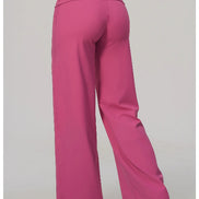 A person shown from the back wearing bright pink wide-leg pants against a plain light gray studio background.