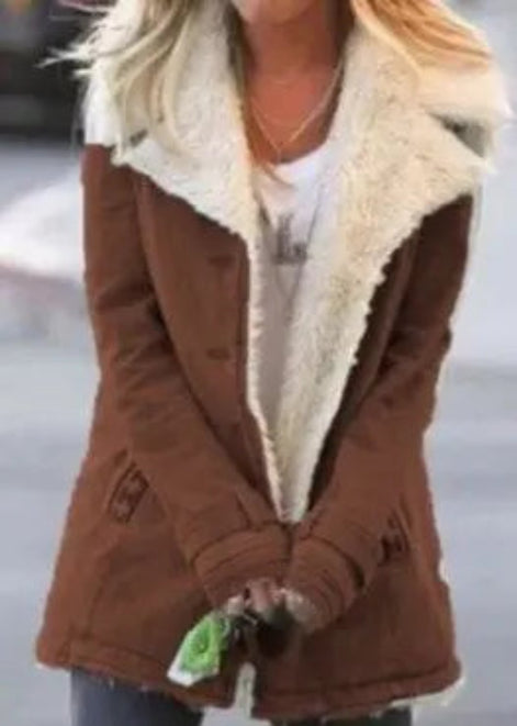 Front view of a woman wearing a brown coat with wide cream fleece-look lapels, cuff tabs and front pockets over a white top⠋