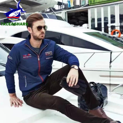 Man in a blue jacket sitting on a boat with a yacht in the background