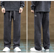Dark gray sweatpants worn by a person on a brown background