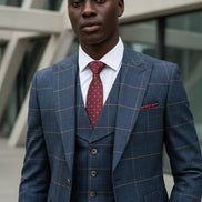Man wearing a blue checkered suit with a red tie in an urban setting