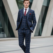 Man wearing a blue checkered suit with a red tie in an urban setting