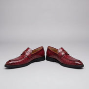 Red leather shoes with a textured pattern worn on a wooden floor.