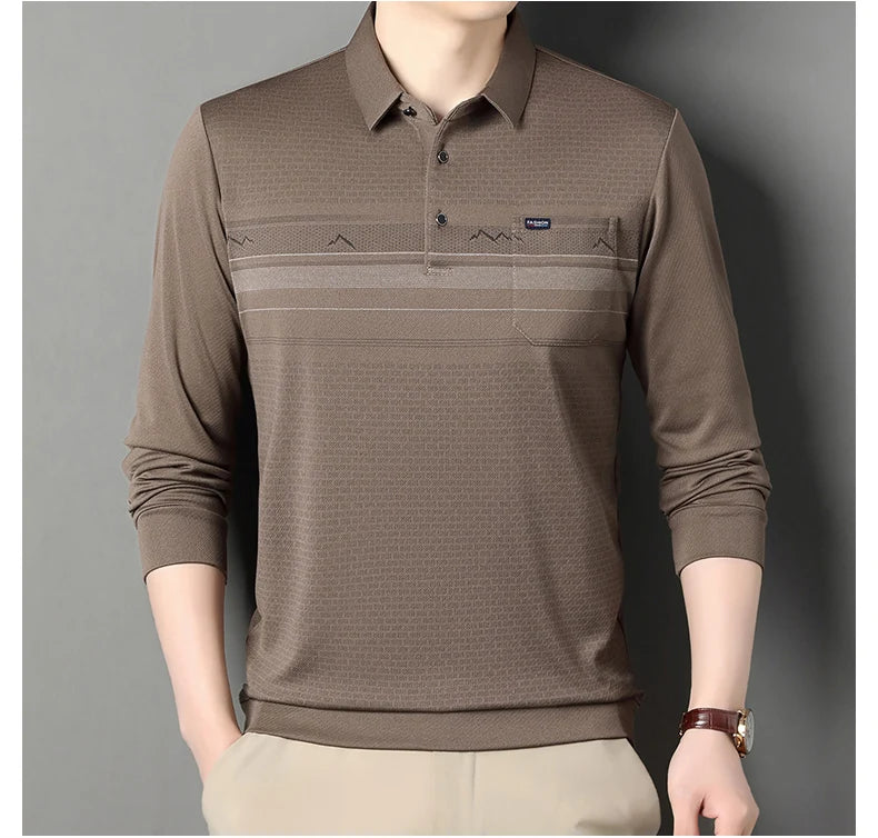 A man wearing a brown long-sleeve polo shirt with a textured pattern and a chest pocket, paired with beige trousers, set against a plain gray background.