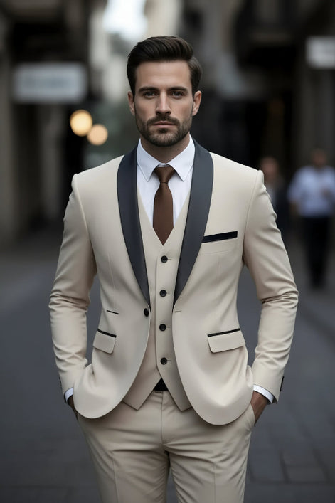 Man wearing a beige suit with black lapels and a brown tie against a blurred background