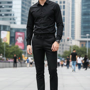 Black dress shoes with gold accents worn by a person on a light gray background