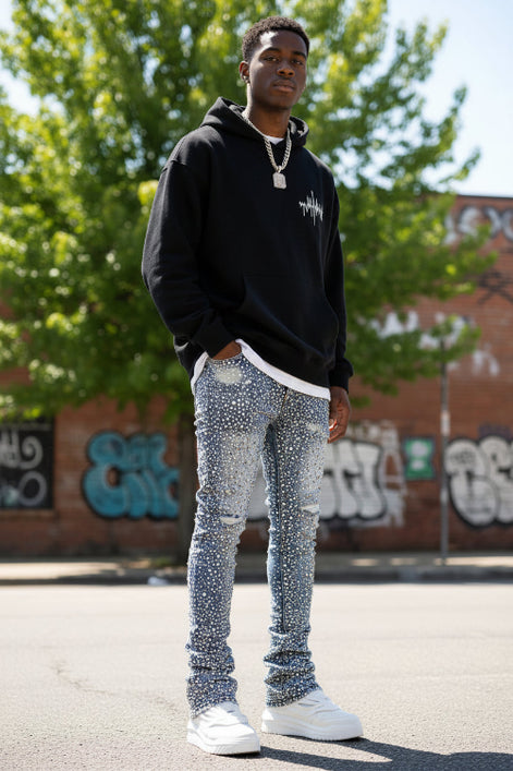 Distressed blue jeans worn with white sneakers on a light gray background